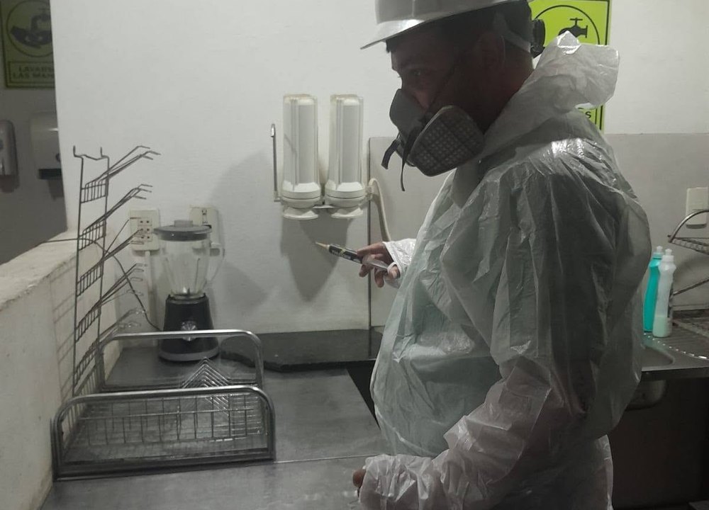 Técnico de Fumigari con equipo de protección fumigando la cocina de un local gastronómico