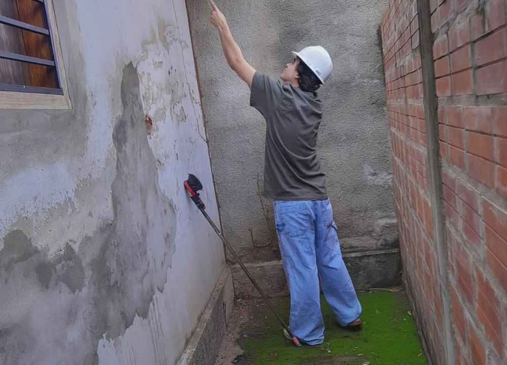 Técnico de Fumigari aplicando producto en la pared exterior de una casa